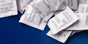 A pile of silica gel desiccant bags on a blue cloth